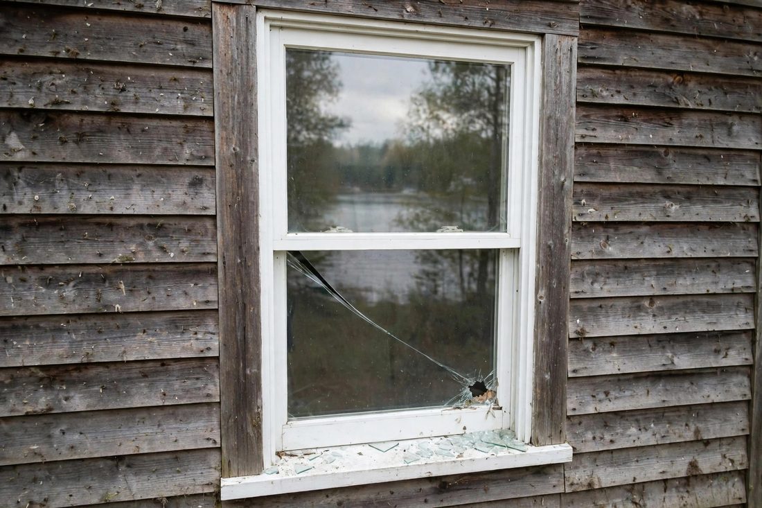 Broken lower pane in a double-hung window, glass shards on the sill